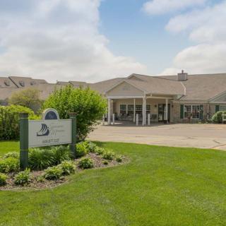 A well-maintained building with a manicured lawn and a sign in front, under a partly cloudy sky.