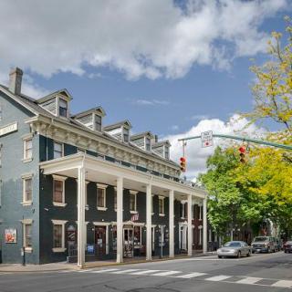 A historic building stands on a street corner under a partly cloudy sky, with autumn trees nearby.