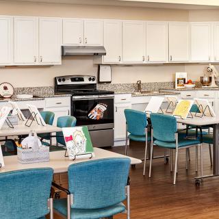 A multipurpose room with kitchen facilities and tables set up for a classroom setting.