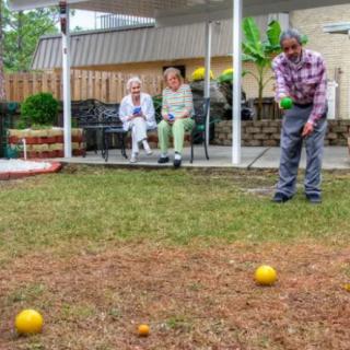 A group of seniors enjoying a leisurely game of bocce in the yard.