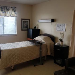 A simple bedroom with a single bed, television, and window.