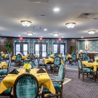 Elegant dining room with yellow table settings and plush blue chairs.