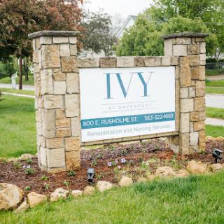 A stone sign for Ivy, surrounded by lush green grass and trees.