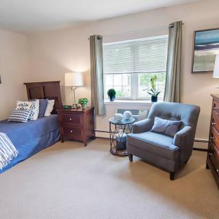 A cozy bedroom with a bed, armchair, and warm lighting.