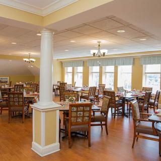 A spacious dining room with wooden tables and chairs, featuring large windows that allow natural light to fill the space.