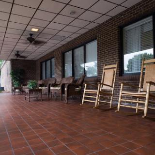A peaceful porch area featuring rocking chairs and ceiling fans, perfect for relaxation.