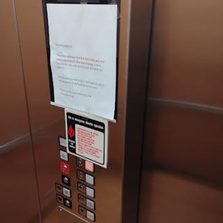 An elevator interior featuring a notice on the wall with several operational buttons.