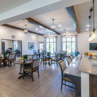 A spacious dining area with multiple tables and chairs, featuring large windows and elegant lighting.