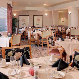 A spacious and elegantly set dining room in a restaurant, featuring neatly arranged tables and chairs.