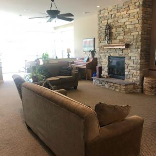 A cozy living room featuring a stone fireplace, comfortable seating, and a ceiling fan.