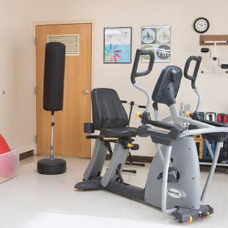 A well-equipped fitness room featuring a recumbent bike and a punching bag, ideal for exercise and rehabilitation.