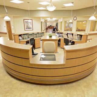 A modern hospital reception area with a wooden front desk and comfortable seating.