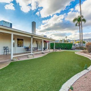 A house with a spacious backyard featuring a patio and lawn under a partly cloudy sky.