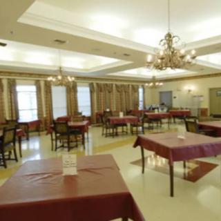 A spacious dining room with neatly arranged tables and elegant chandeliers.