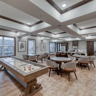 A modern game room featuring a shuffleboard table and seating area.