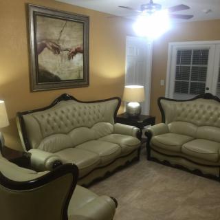 A well-decorated living room featuring an elegant sofa set, ambient lighting, and a prominent painting on the wall.