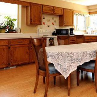 A cozy kitchen with wooden cabinets and a dining table draped with a lace tablecloth.