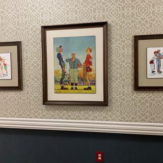 Three framed artworks hanging on a patterned wall in a hallway.