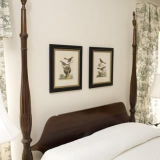 A cozy bedroom featuring a four-poster bed with two framed bird artworks on the wall.