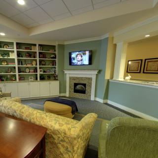 A cozy living room with a fireplace, television, and bookshelves.
