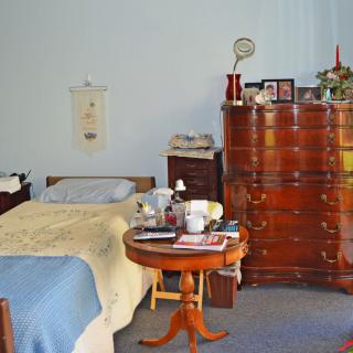 A cozy bedroom with a single bed, a wooden dresser, and a round table.