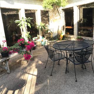 A serene outdoor patio adorned with plants and a cozy table setting.