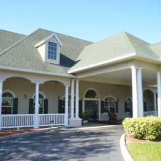 A large house with a covered porch and driveway, featuring traditional architecture.