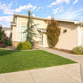 A suburban house with a well-maintained lawn and clear blue sky.