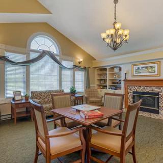 A cozy living room with a chandelier, fireplace, and a wooden table surrounded by chairs.