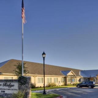 A building with a sign and an American flag in front, alongside a vehicle parked nearby.