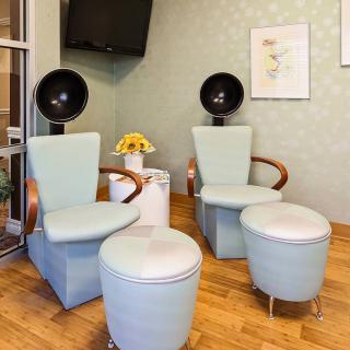 A modern salon seating area with stylish chairs and hair dryers.