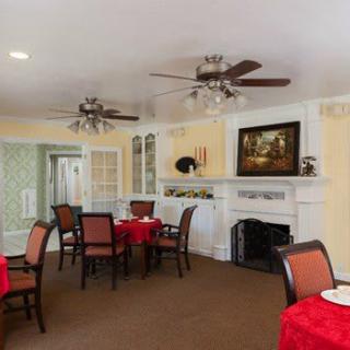 A cozy dining room with red tablecloths, ceiling fans, and a fireplace.