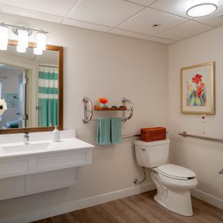 A modern bathroom featuring a clean design with a toilet, sink, and mirror, complemented by wall art and decorative towels.
