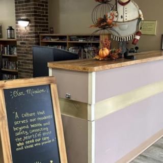 A restaurant reception area featuring a chalkboard with a welcoming message and decorative elements.