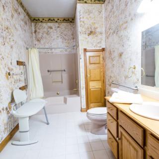 A vintage-style bathroom with wooden cabinetry and floral wallpaper.