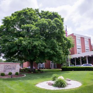 A building surrounded by lush greenery and a large tree.