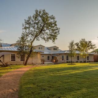 A charming residential house with a well-maintained lawn and trees at sunset.