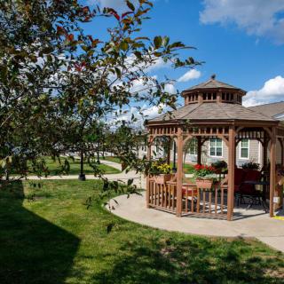 A picturesque gazebo in a lush garden setting under a clear blue sky.