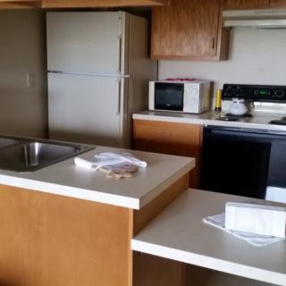 A cozy kitchen with modern appliances, including a refrigerator, microwave, and stove.