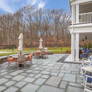 Spacious outdoor patio with seating and umbrellas overlooking a wooded area.