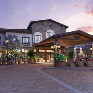 A beautifully landscaped hotel entrance with a fountain and elegant architecture at dusk.