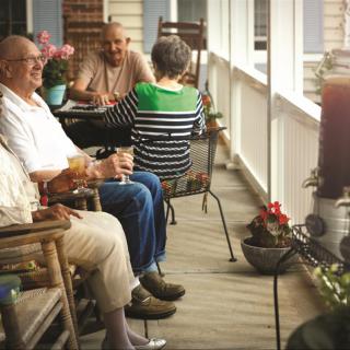 A group of seniors enjoying a conversation on a cozy porch.