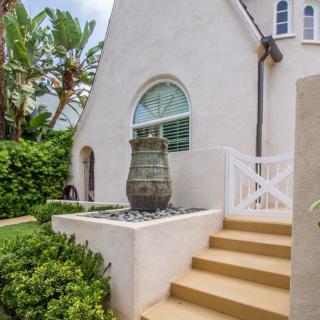A charming house exterior with a garden, staircase, and decorative features.