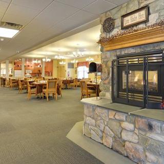 A cozy restaurant interior featuring a stone fireplace and wooden tables and chairs.