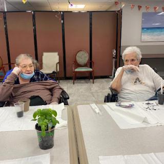 Two elderly individuals enjoying their time together in a care facility.