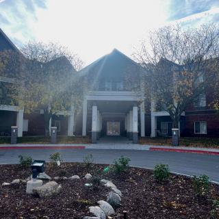 A building with a central entrance surrounded by landscaping and a circular driveway.