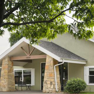 A quaint residential building with a front entrance and surrounding greenery.
