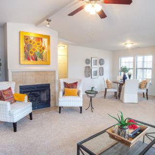 A modern living room with comfortable seating, a fireplace, and a dining area in the background.