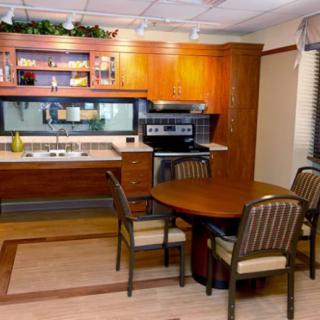 A modern kitchen featuring wooden cabinets, a dining table with chairs, and various appliances.