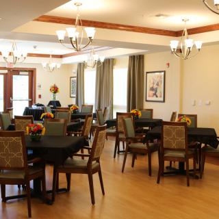 A well-lit dining area featuring several tables and chairs, adorned with chandeliers and tasteful decorations.
